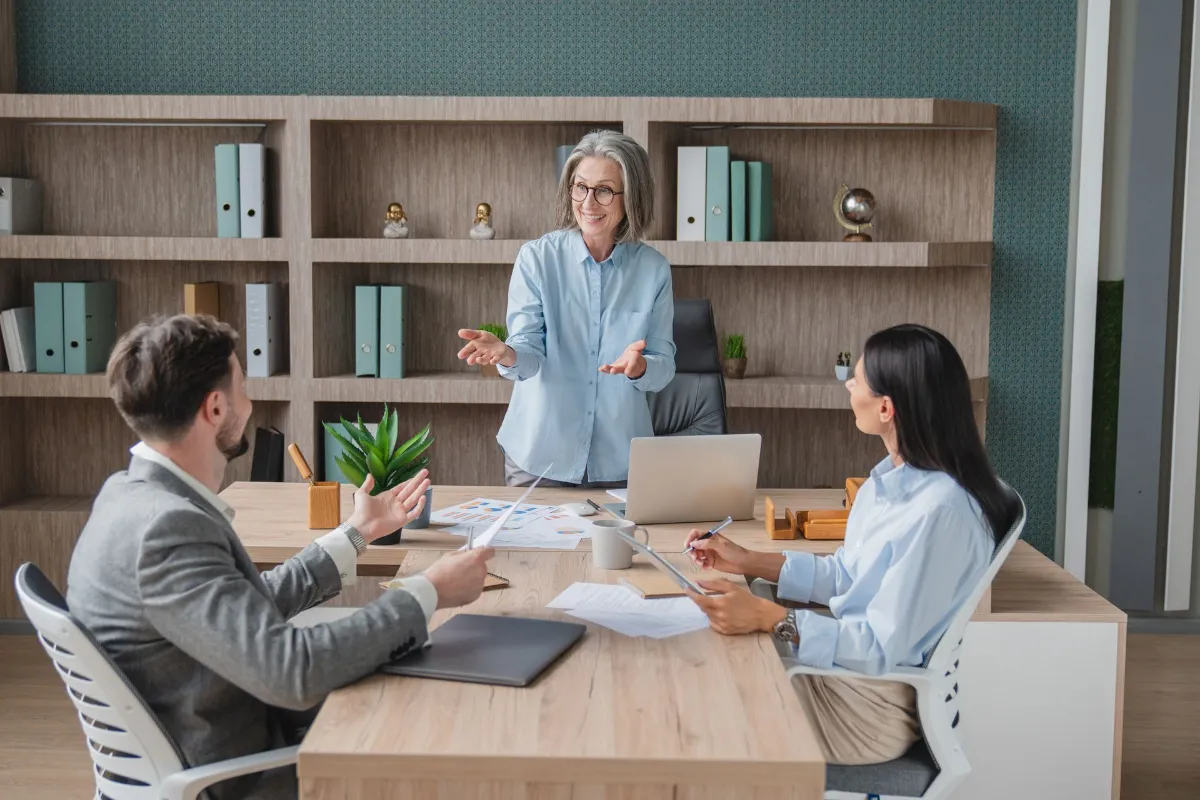 Senior older female executive ceo leader and smiling group of business people discussing
